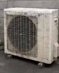 全体に黒い汚れが付着したエアコンの室外機